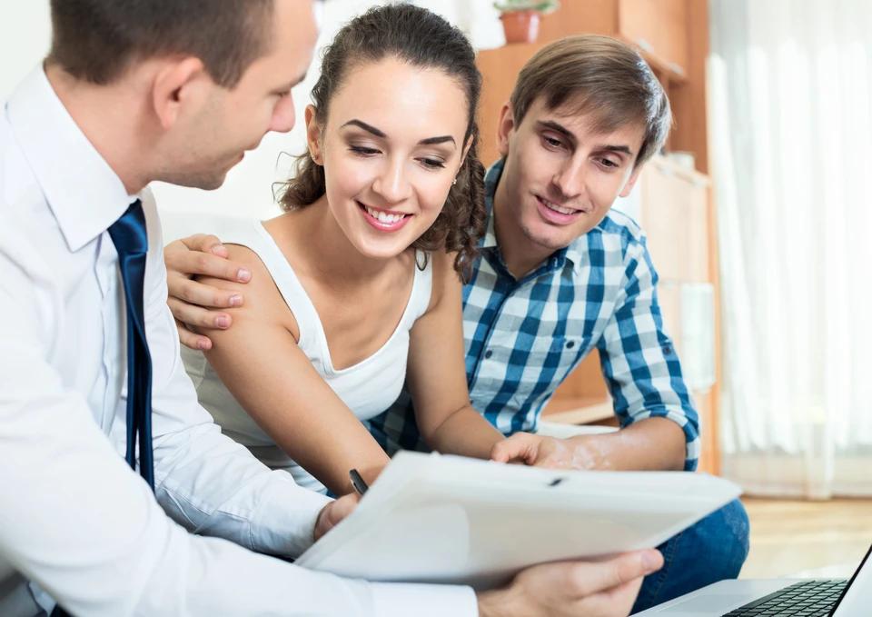 Femme d'affaires souriante en costume noir et chemise bleue, lunettes, travaillant à son bureau dans un environnement professionnel moderne