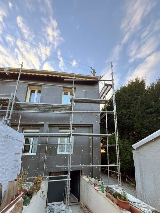 Chantier de rénovation extérieure d'une maison individuelle avec échafaudage métallique tubulaire installé sur façade